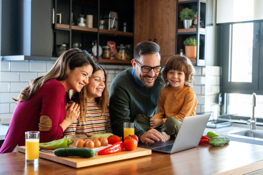 Parents and child relaxing at home with computer watching funny internet video, making online call