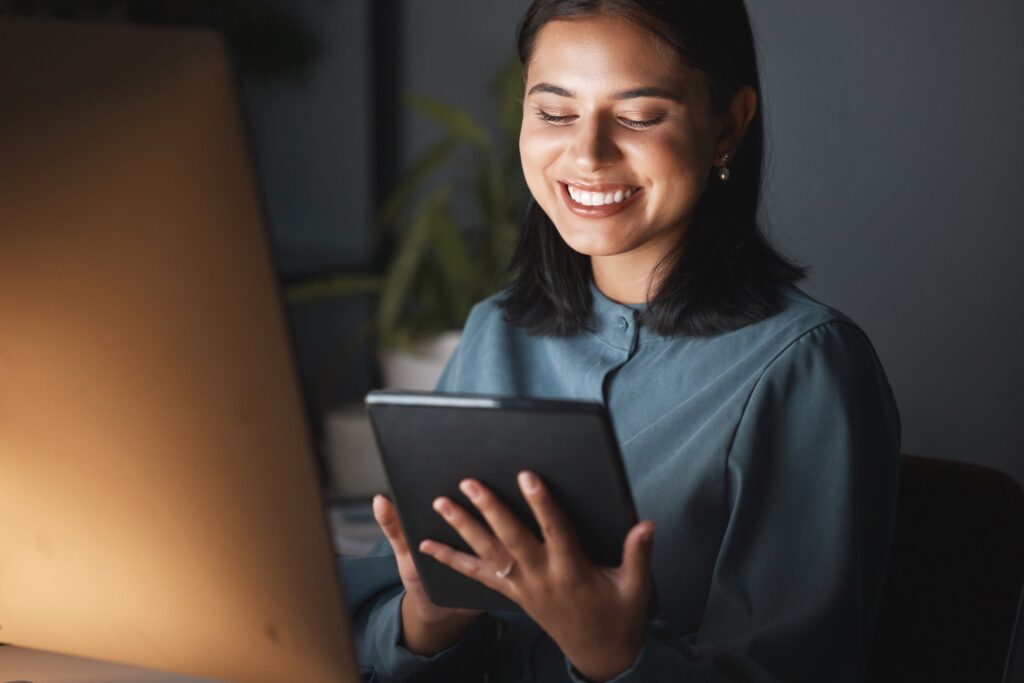 Woman, tablet and happy on internet at night in office, working and digital marketing on mobile tec